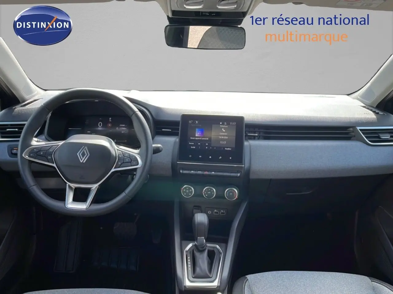 Vue intérieure avant de la Renault Clio 2025, tableau de bord moderne avec écran tactile et volant multifonction noir.