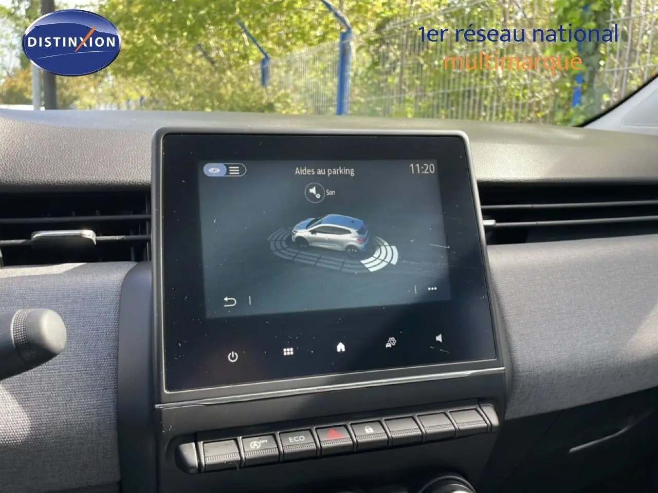 Écran tactile central de la Renault Clio gris schiste 2025 affichant l’aide au parking, avec tableau de bord gris textile.