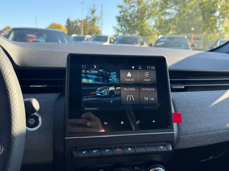 Vue intérieure centrée sur l'écran tactile du tableau de bord de la Renault Clio orange Valencia 2025.