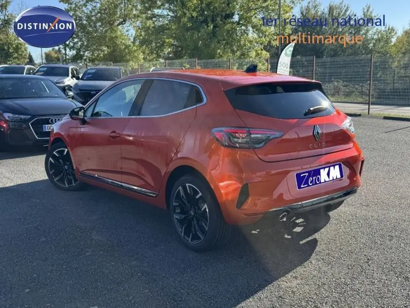 Renault Clio orange Valencia vue 3/4 arrière droit, jantes alu noires et vitres arrière teintées.