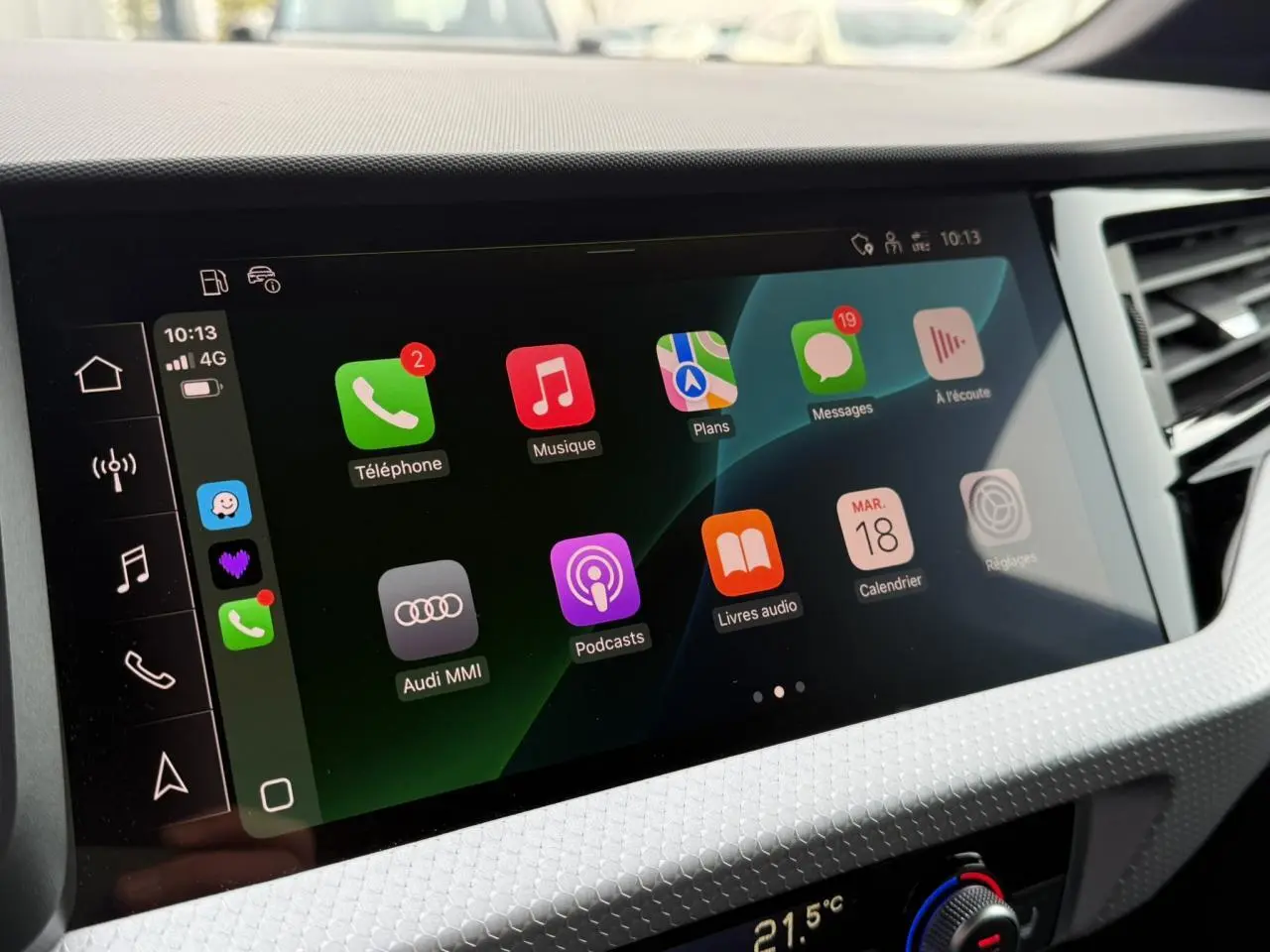 Écran tactile central de l'Audi A1 Sportback 2023 affichant Apple CarPlay avec icônes colorées sur fond noir.