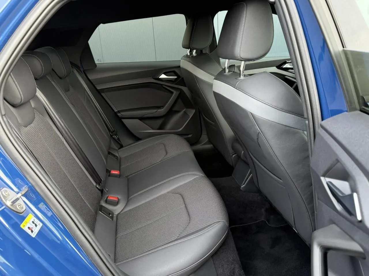 Vue côté gauche de l'habitacle arrière d'une Audi A1 Sportback bleu Ascari avec sièges sport cuir/tissu noirs.