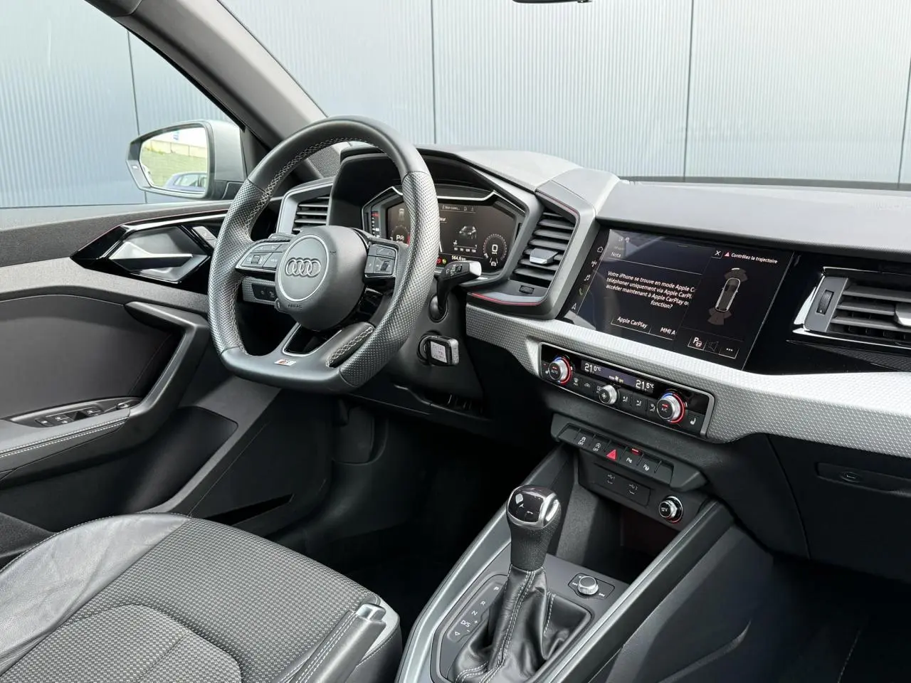 Intérieur avant de l'Audi A1 Sportback 30 TFSI bleu Ascari, volant cuir sport, tableau de bord numérique et écran tactile.