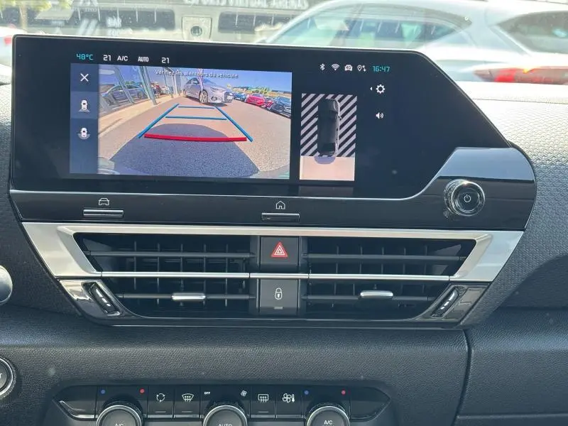 Écran tactile intérieur de la Citroën C4 X rouge Elixir affichant la caméra de recul et l'aide au stationnement.