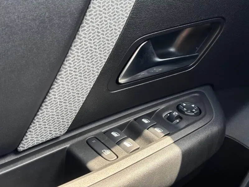 Gros plan sur la commande des vitres et le bouton de réglage des rétroviseurs côté conducteur du Citroën C4 X rouge Elixir.