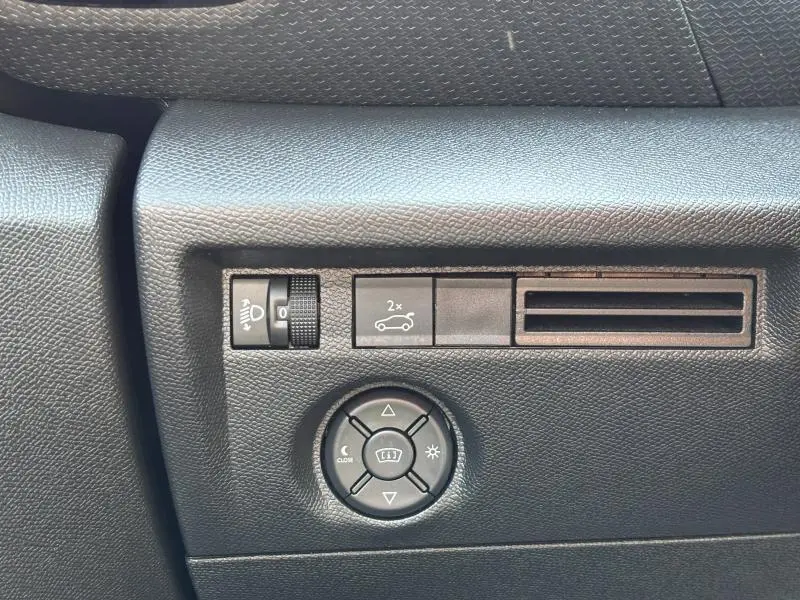 Gros plan sur les commandes noires de réglage des phares et du tableau de bord dans une Citroën C4 X rouge Elixir.