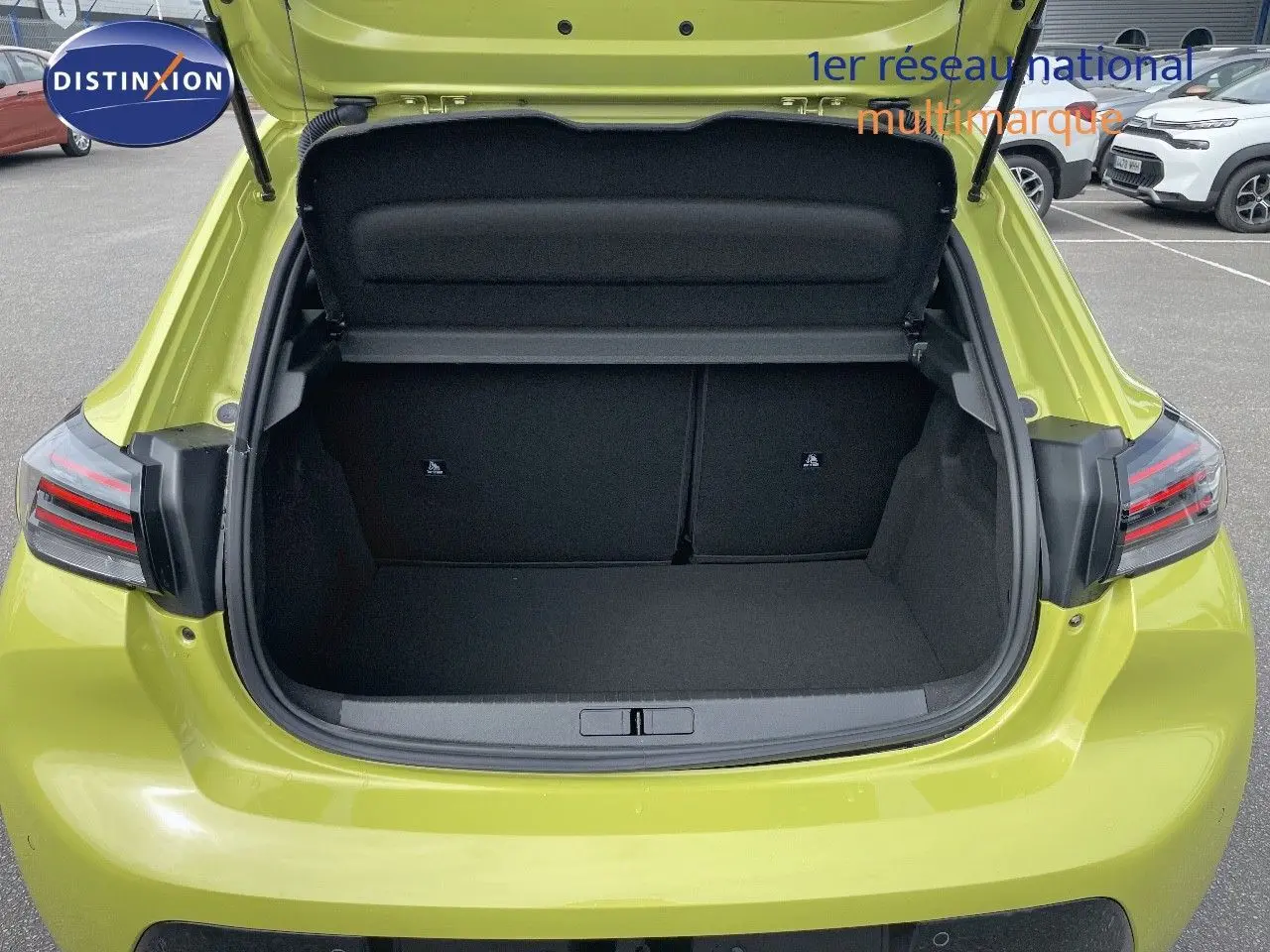 Coffre ouvert vu de l'arrière d'une Peugeot 208 jaune Agueda Metal, montrant l'espace de chargement vide.
