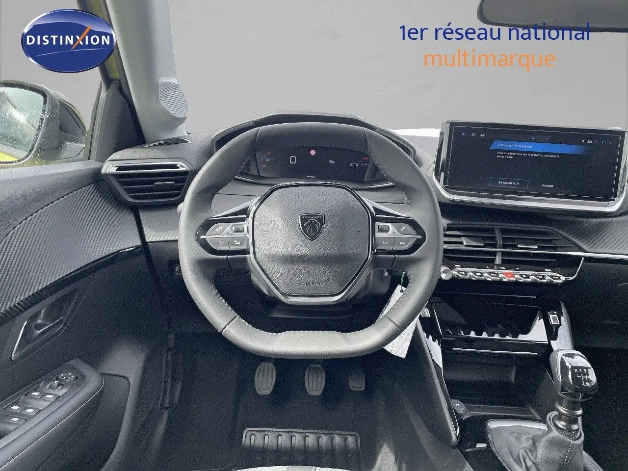 Vue intérieure centrée sur le volant et la console d'une Peugeot 208 jaune Agueda Metal, boîte manuelle visible.