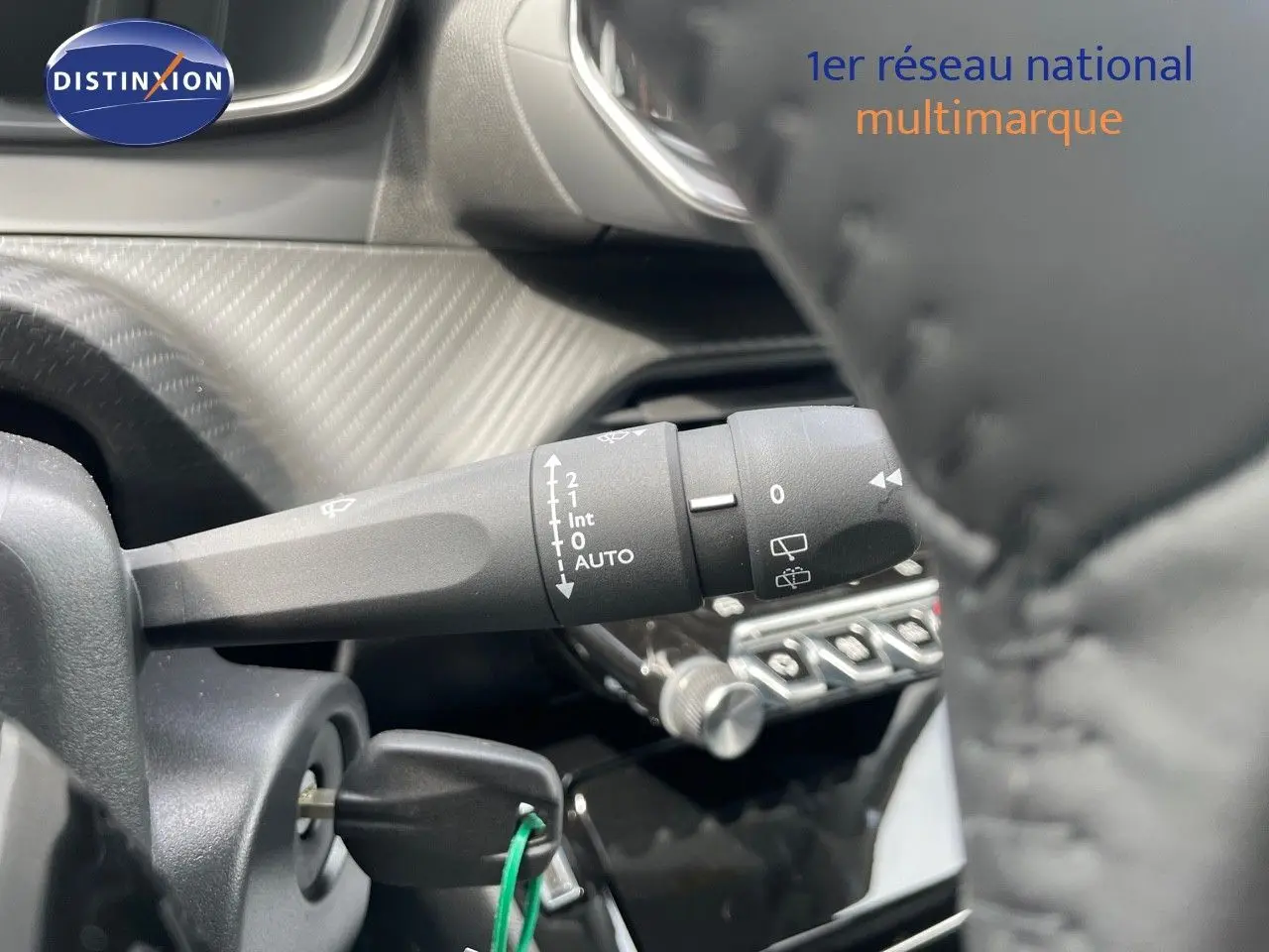 Gros plan sur la commande d’essuie-glace à gauche du volant d’une Peugeot 208 jaune Agueda Metal, intérieur noir.