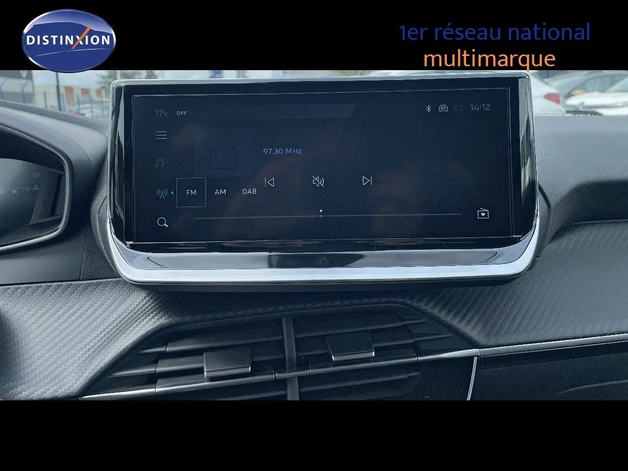 Écran tactile central du tableau de bord de la Peugeot 208 2025, affichant la radio FM, intérieur noir.