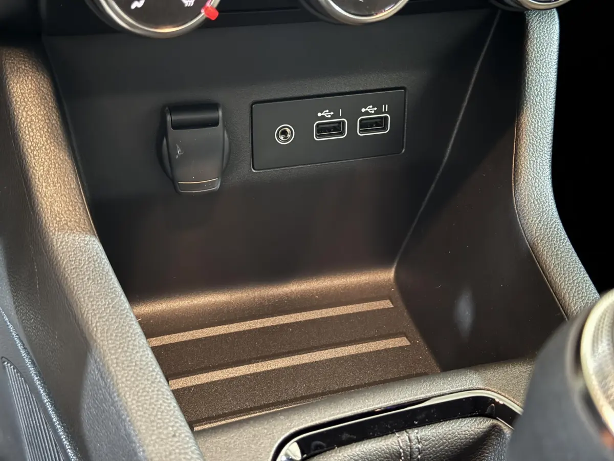 Vue rapprochée de la console centrale noire de la Renault Clio gris clair, montrant deux ports USB et une prise 12V.