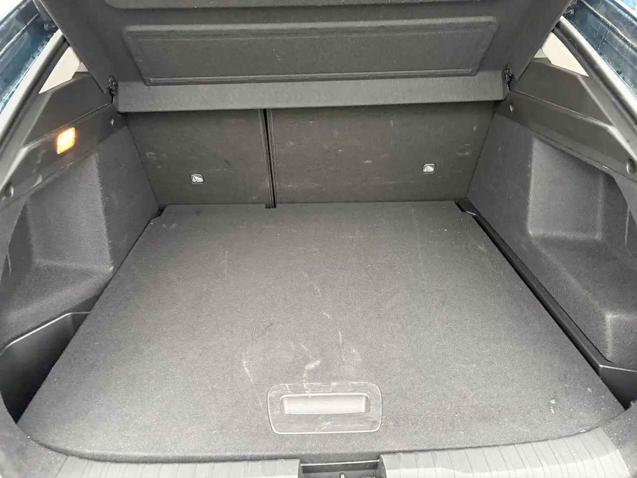 Coffre ouvert vu de l'arrière d'un Renault Arkana Bleu Zanzibar Metal, espace de chargement plat et éclairage intérieur allumé.