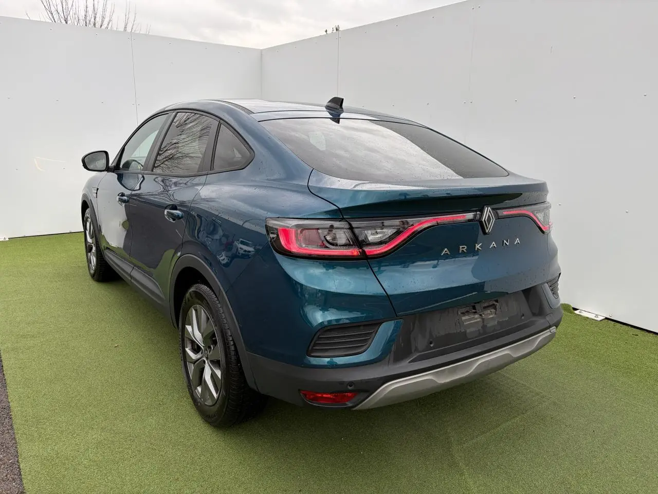 Vue 3/4 arrière droite d'une Renault Arkana 2025 bleu Zanzibar métal avec feux arrière LED et vitres surteintées.