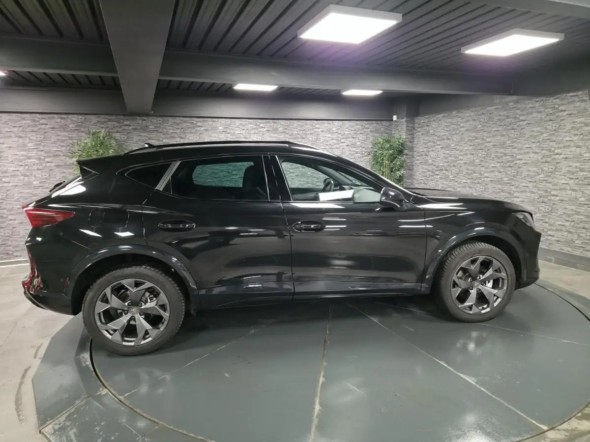 Vue de profil côté gauche du CUPRA Formentor noir 2025 dans un showroom avec jantes alliage et toit panoramique.