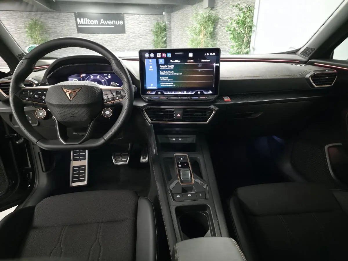 Vue intérieure avant du CUPRA Formentor noir, tableau de bord avec écran tactile central et volant sport multifonction.