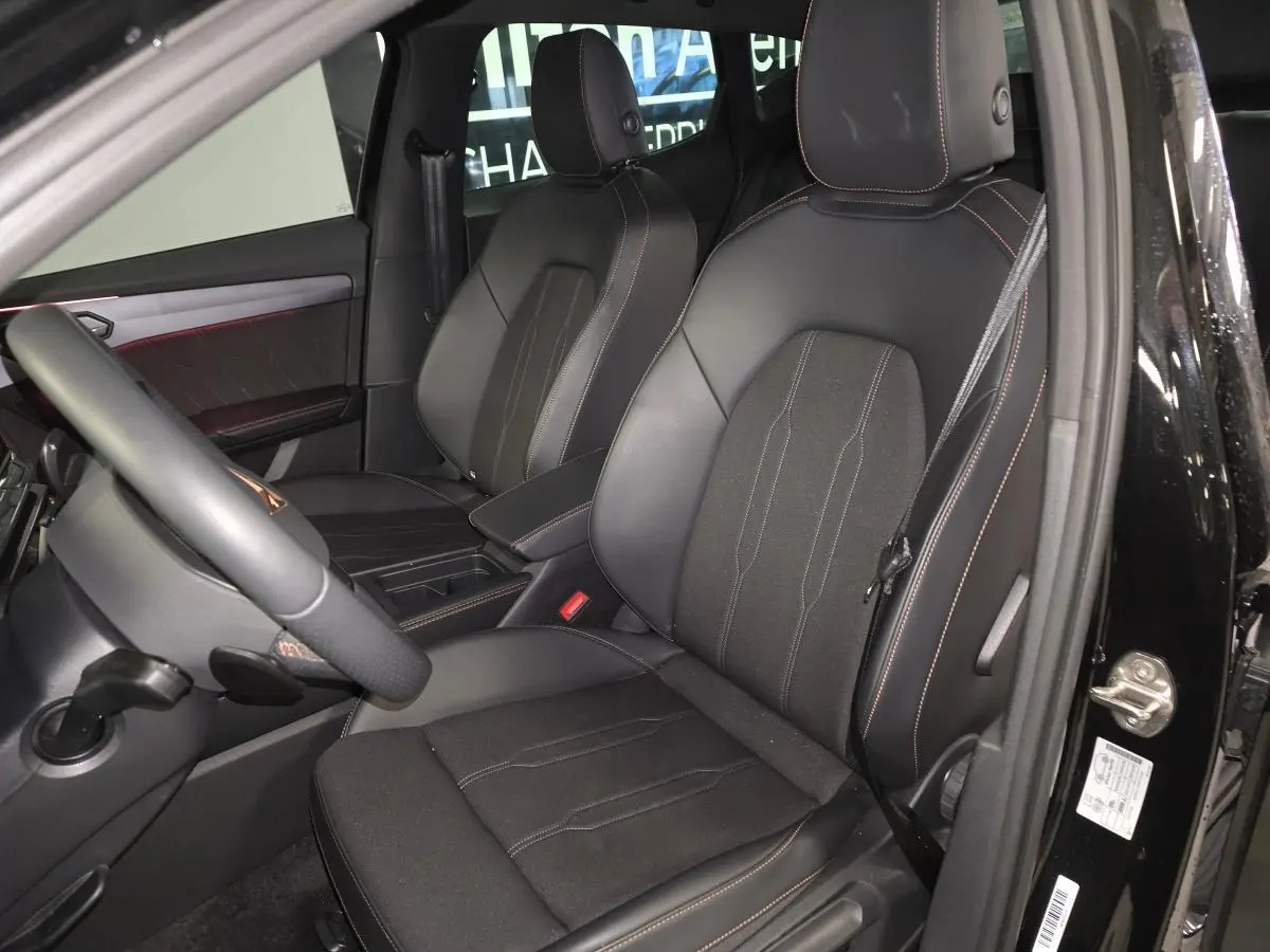 Vue intérieure côté conducteur du CUPRA Formentor noir, sièges sport bimatière avec surpiqûres cuivrées et volant cuir.