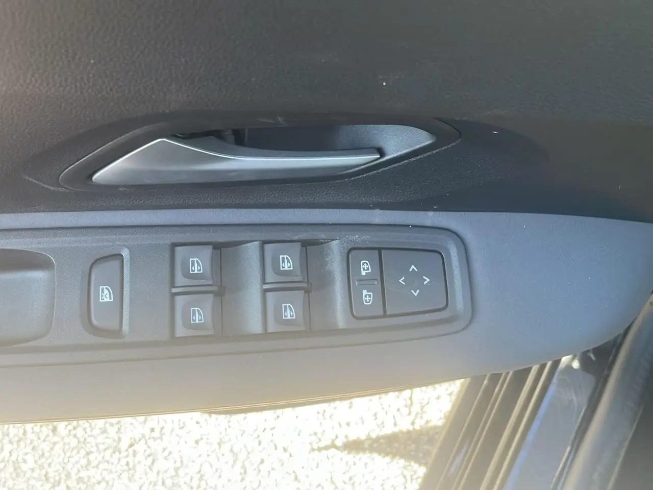 Gros plan sur la commande des vitres électriques et rétroviseurs côté gauche d'une Dacia Jogger noir nacré 2024.