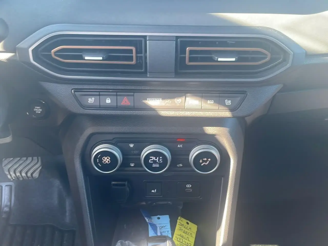 Tableau de bord central du Dacia Jogger 2024 avec commandes climatisation et boutons fonctionnels en vue frontale rapprochée.