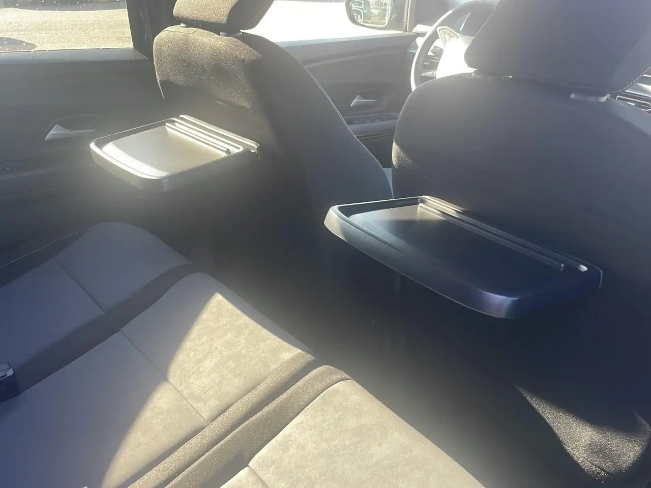Vue intérieure arrière du Dacia Jogger 2024 avec tablettes rabattables sur les dossiers des sièges avant et banquette 3 places grise.