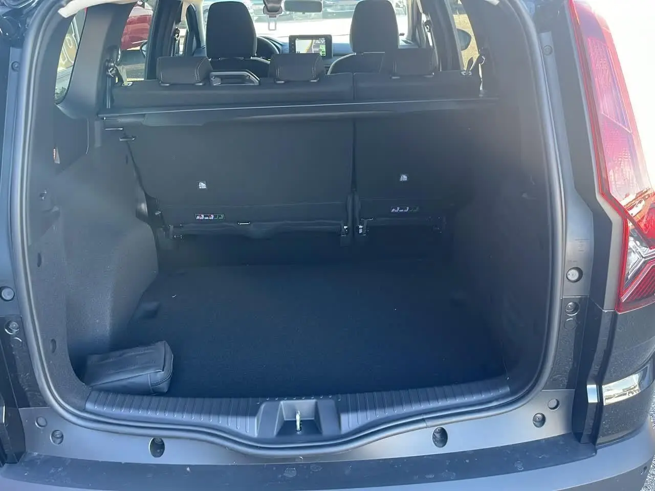 Coffre ouvert d'un Dacia Jogger noir nacré 2024, vue arrière montrant banquette rabattable et tablette cache-bagages.