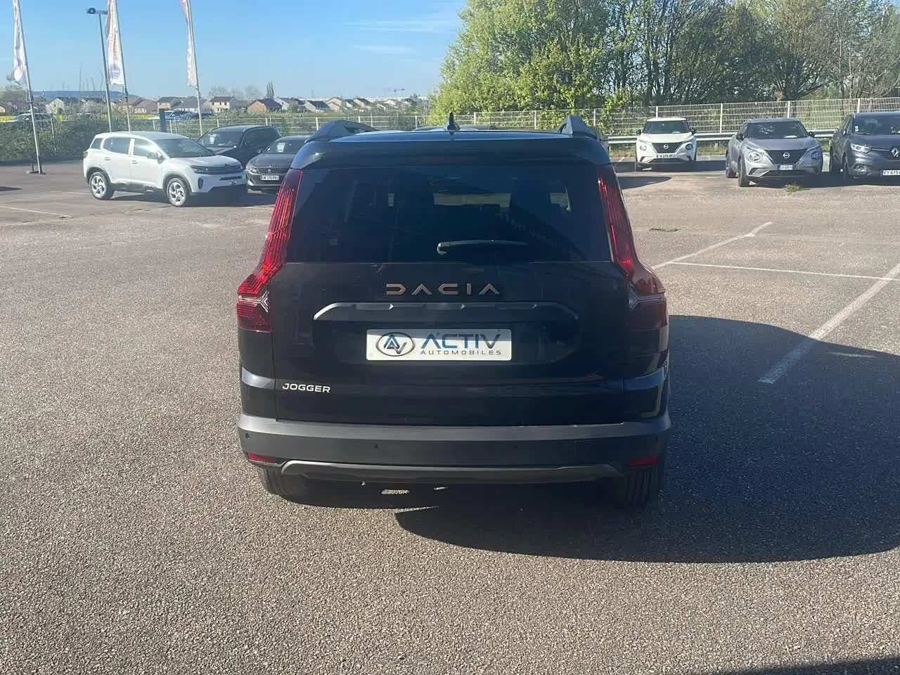 Vue arrière d'un Dacia Jogger noir nacré 2024 avec feux arrière verticaux et logo Dacia lumineux.