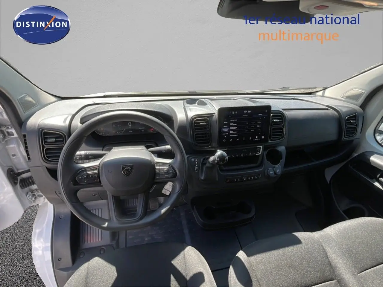 Vue intérieure avant du Peugeot Boxer Fourgon blanc banquise, mettant en valeur le tableau de bord et le volant multifonction.