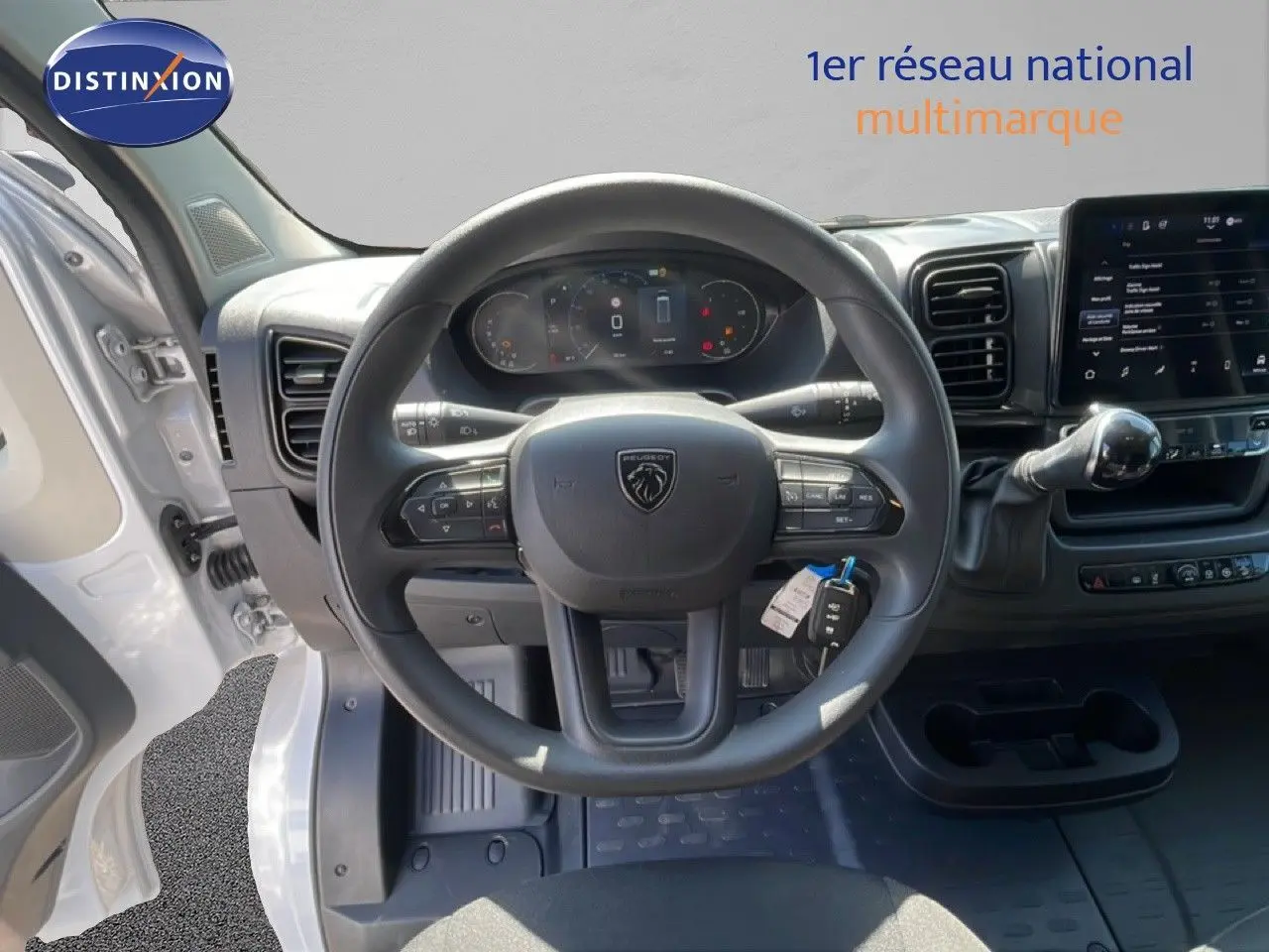 Vue intérieure centrée sur le volant Peugeot d’un Boxer Fourgon blanc banquise avec tableau de bord numérique et écran tactile.