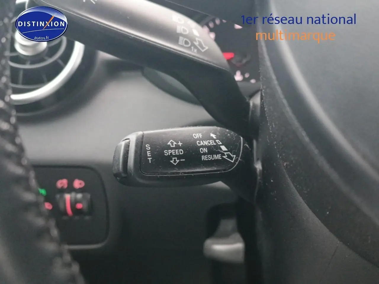 Gros plan sur la commande de régulateur de vitesse noire dans l’habitacle d’une Audi A1 blanche de 2015.