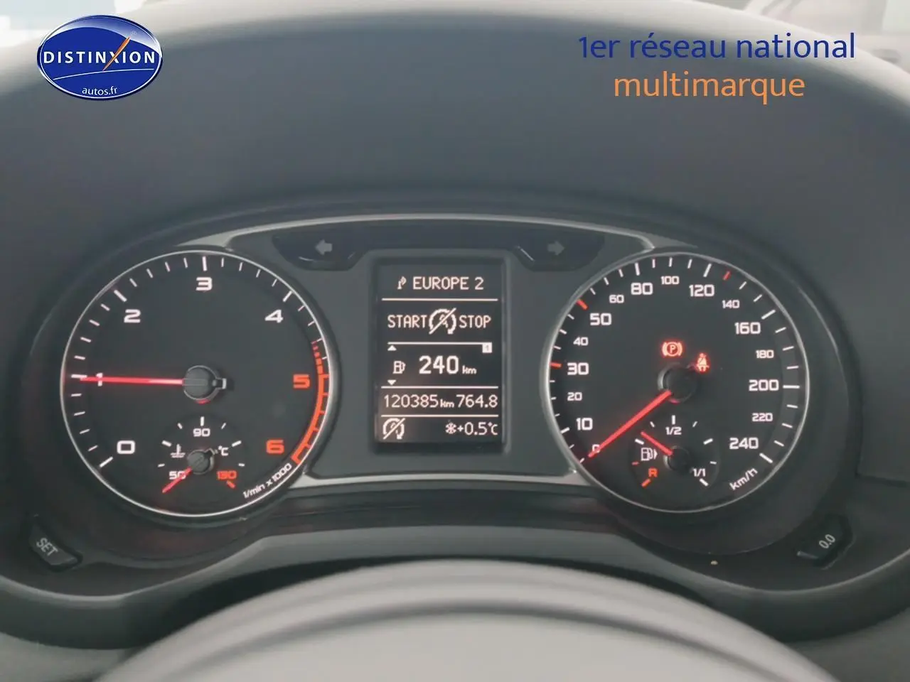 Vue rapprochée du tableau de bord de l'Audi A1 blanc 2015, affichant compteurs et écran multifonction digital.