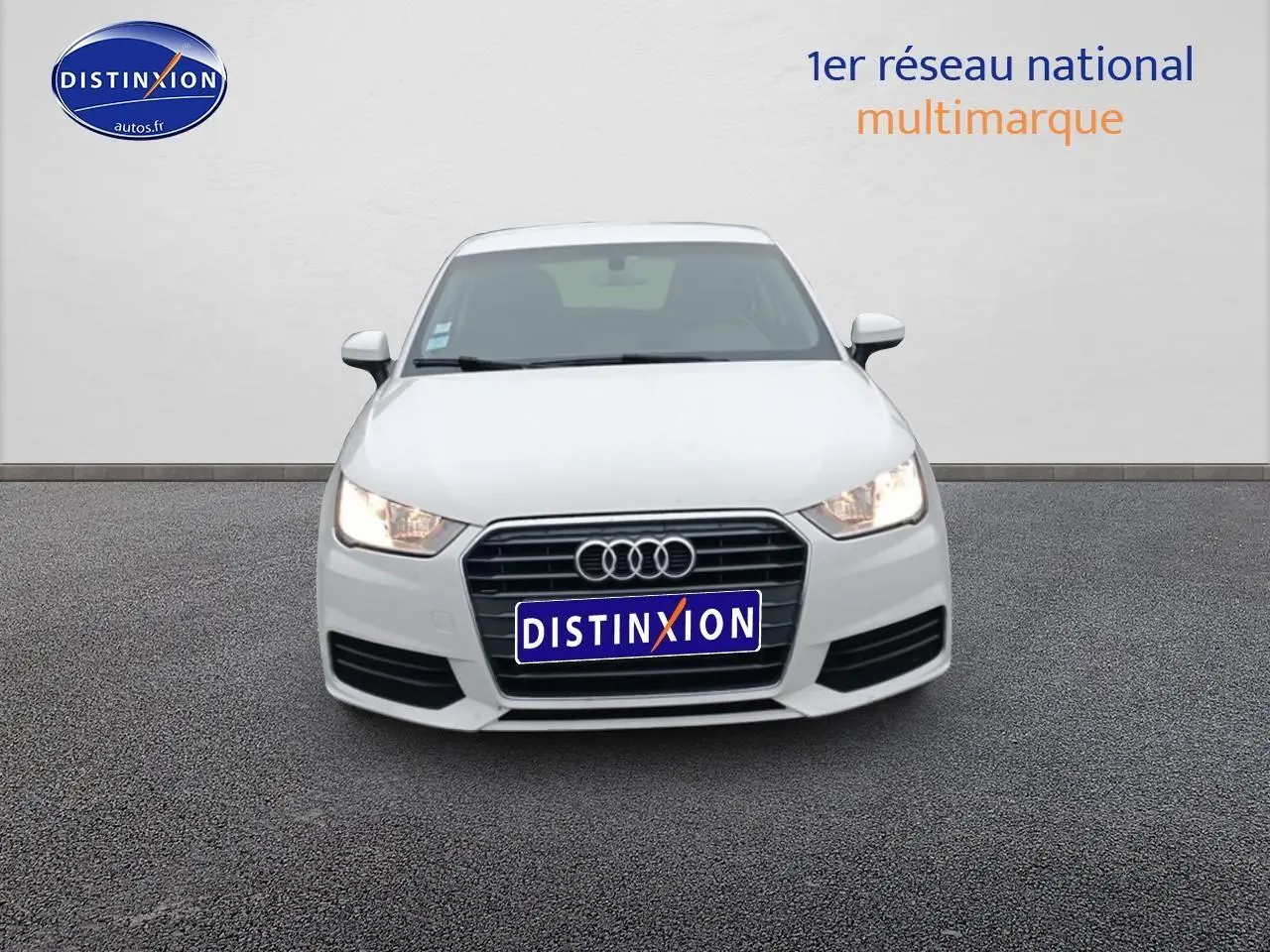 Vue avant d'une Audi A1 blanche de 2015 avec phares allumés et calandre noire distinctive.