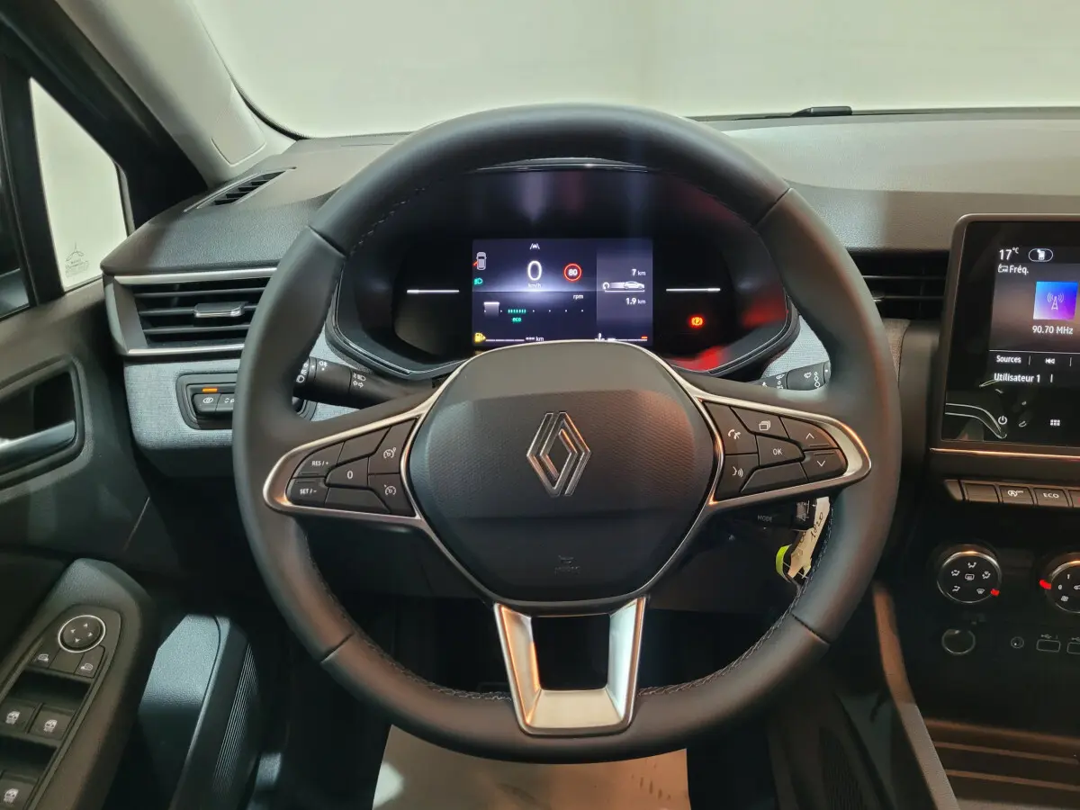 Vue intérieure centrée sur le volant cuir noir de la Renault Clio 2025 avec tableau de bord digital et écran tactile.