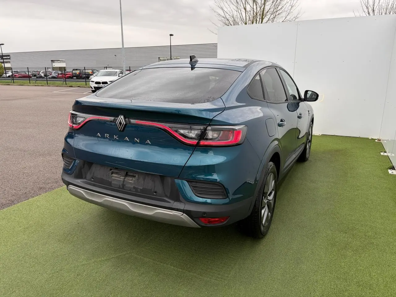 Vue 3/4 arrière droite d'une Renault Arkana bleu Zanzibar avec feux arrière LED et vitres surteintées.