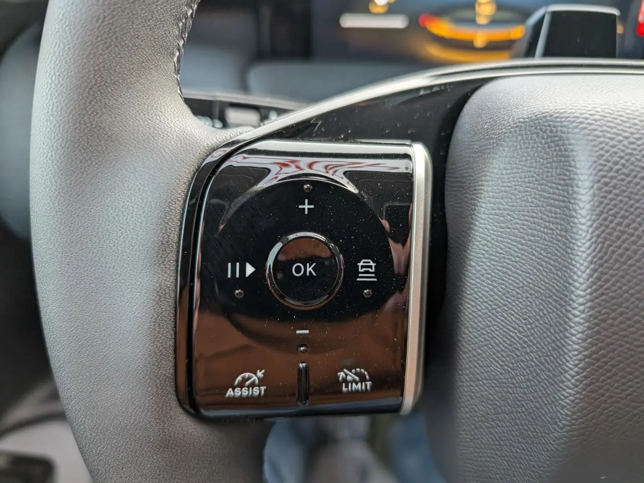 Gros plan sur les commandes noires du volant gris du Citroën C5 Aircross hybride, avec boutons multifonctions et symbole d'assistance.