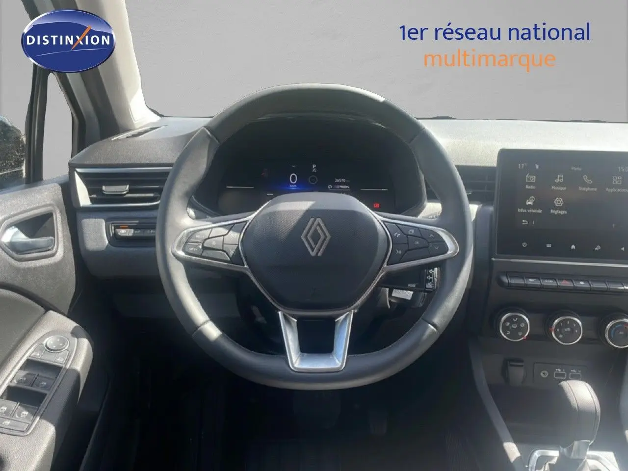 Vue centrée sur le volant et le tableau de bord noir d'une Renault Clio 2025 avec écran tactile et commandes intégrées.