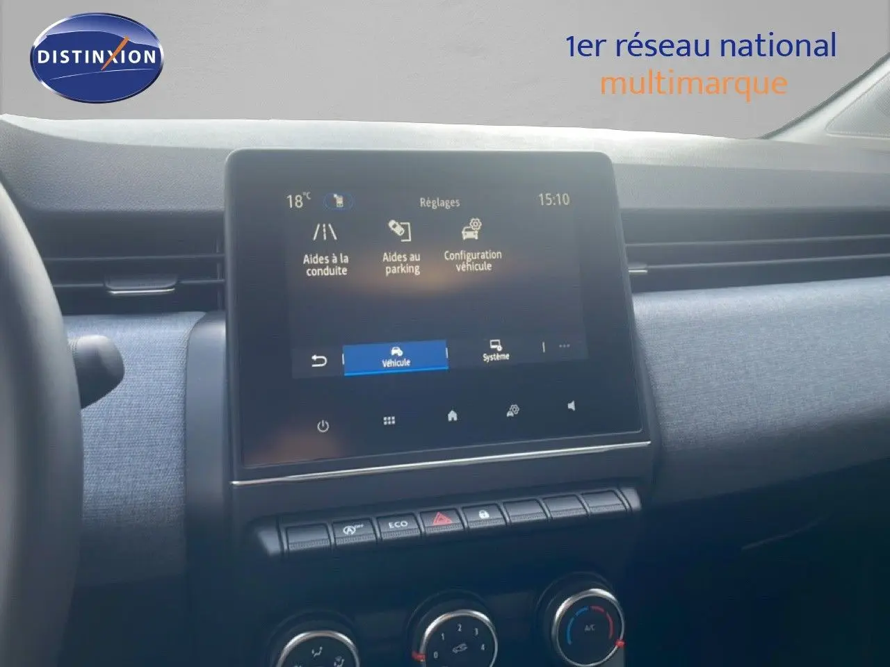Vue intérieure centrée sur l'écran tactile et la console centrale d'une Renault Clio blanche, avec tableau de bord gris.