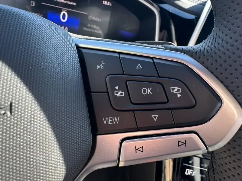 Gros plan sur les commandes multifonctions noires et argent du volant cuir perforé du Volkswagen T-Roc 2025 noir intense nacré.
