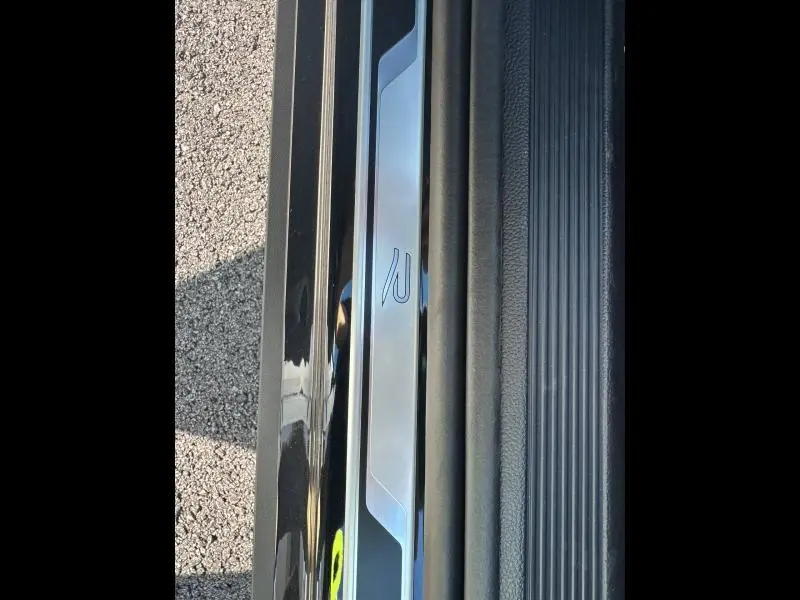 Gros plan sur la plaque de seuil de porte côté gauche du Volkswagen T-Roc noir intense nacré, avec logo R-Line visible.