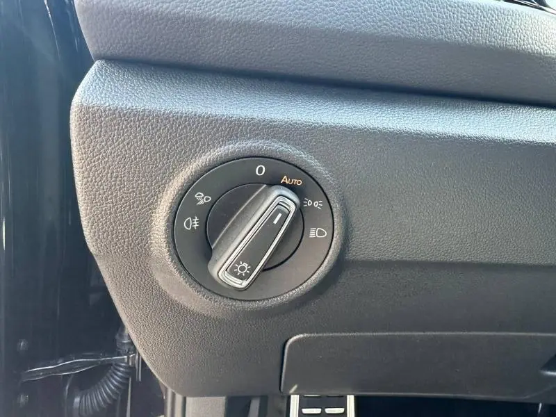 Gros plan sur le bouton de commande des phares noir dans l'habitacle du Volkswagen T-Roc noir nacré, côté conducteur.