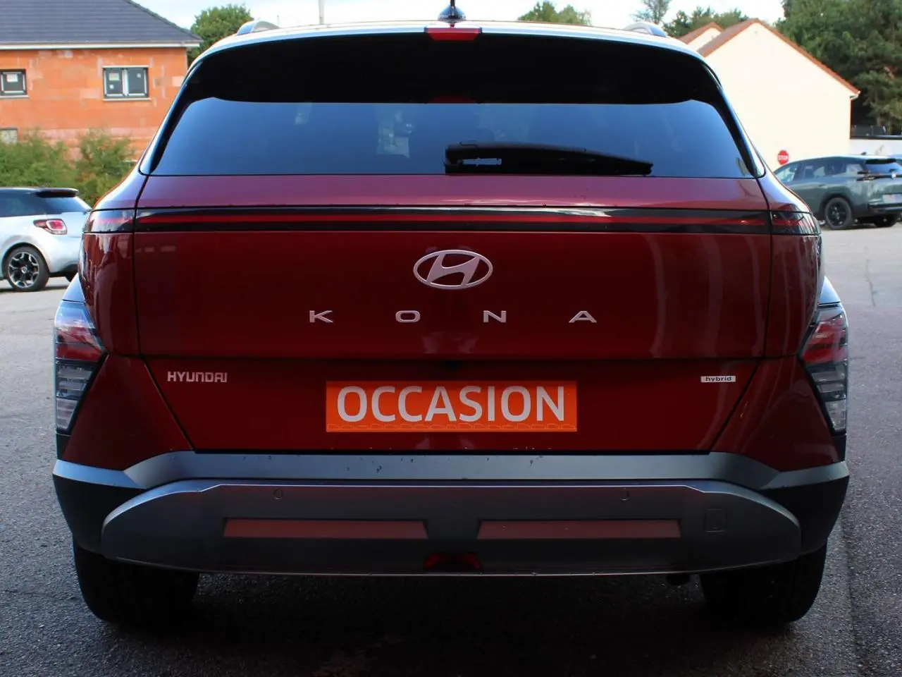 Vue arrière d’un Hyundai Kona rouge Ultimate Metal avec toit noir, badge hybride et plaque « Occasion » visible.