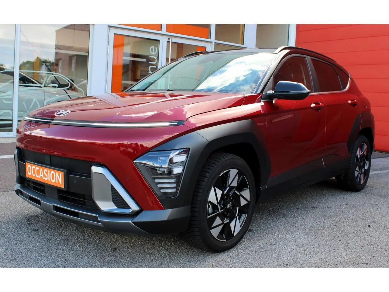 Vue 3/4 avant gauche d'un Hyundai Kona 2024 rouge Ultimate Metal avec toit noir et jantes alliage noires.