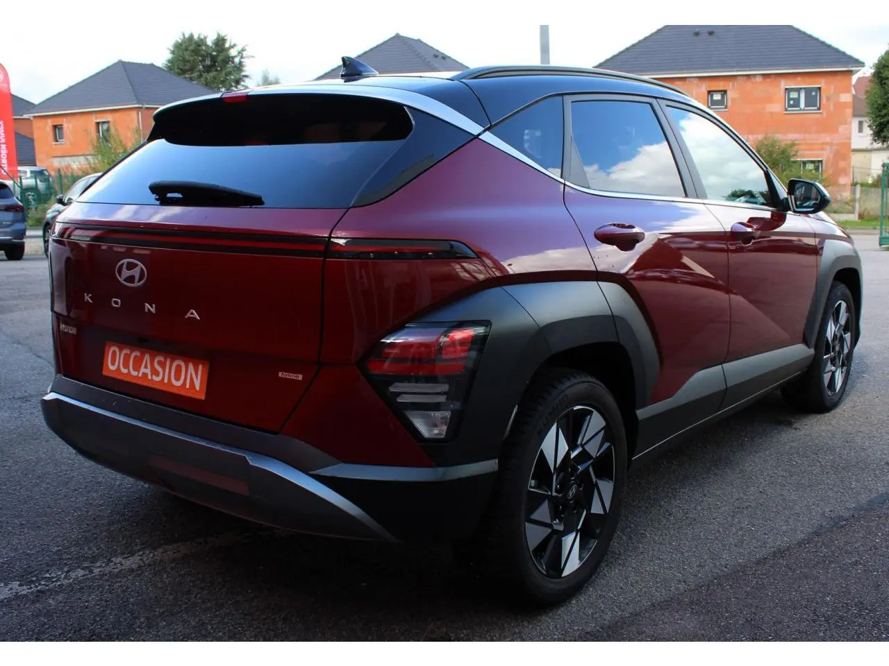 Vue 3/4 arrière droite d'un Hyundai Kona 2024 rouge Ultimate Metal avec toit noir et jantes alliage.