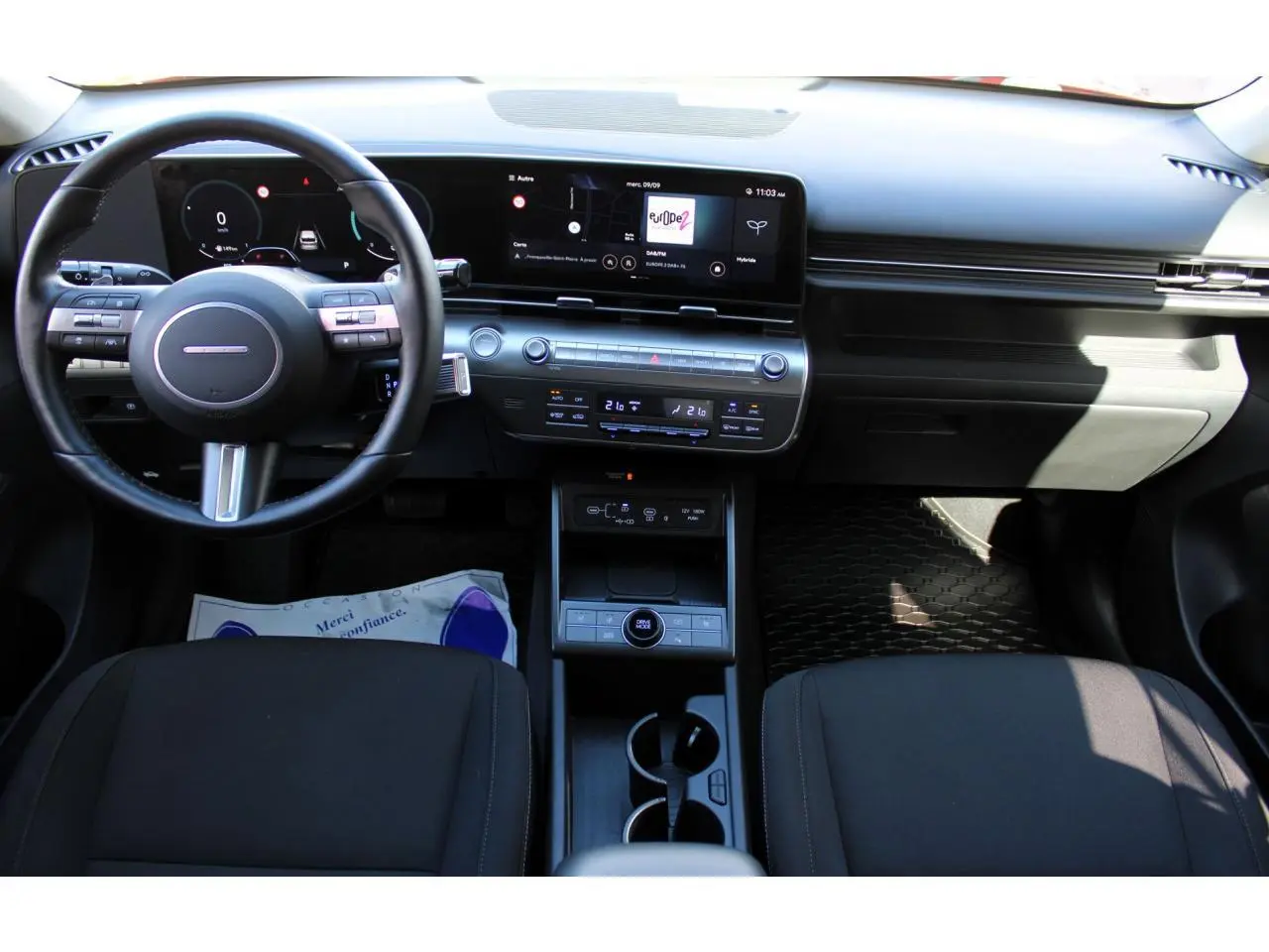 Vue intérieure avant du tableau de bord et volant cuir noir du Hyundai Kona 2024 avec écran tactile large et console centrale moderne.