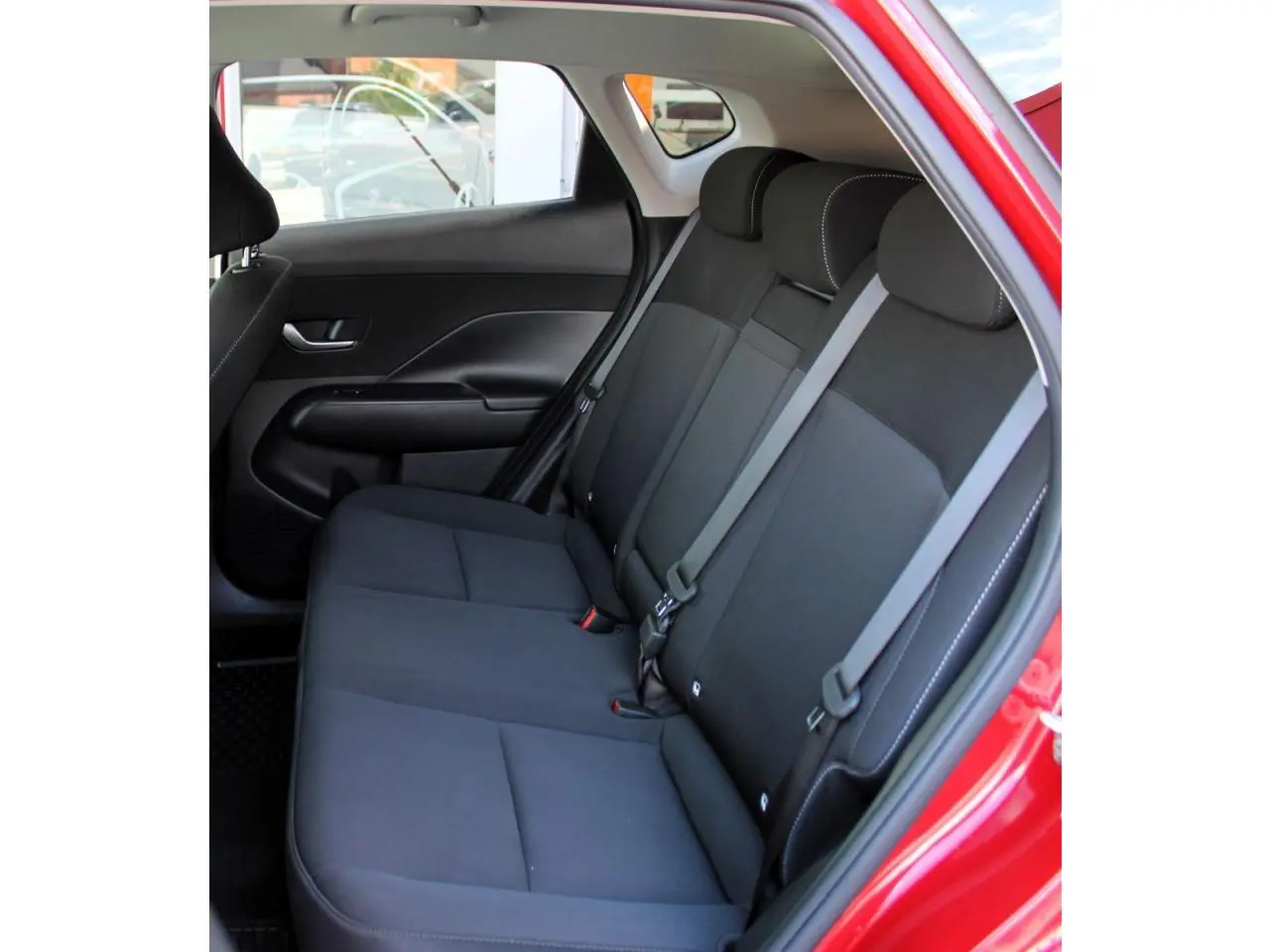 Vue intérieure côté gauche des sièges arrière noirs du Hyundai Kona rouge Ultimate Metal 2024 avec ceinture grise.
