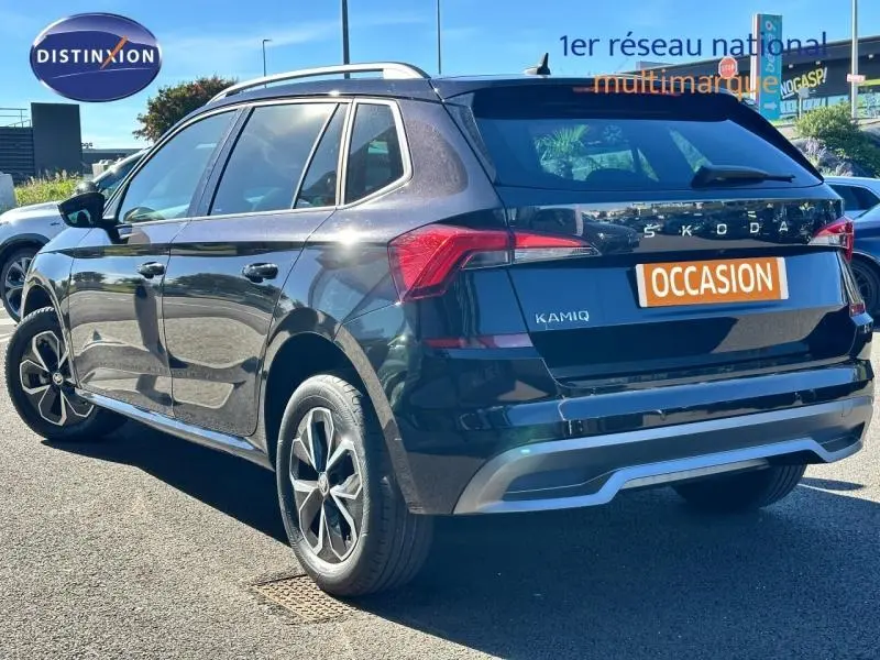 Vue 3/4 arrière droite d'un Skoda Kamiq noir avec jantes alu et feux arrière LED distinctifs sur parking extérieur.