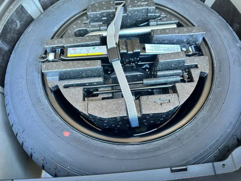 Gros plan sur la roue de secours et le cric rangés dans le coffre du Skoda Kamiq 2020, vue de dessus.