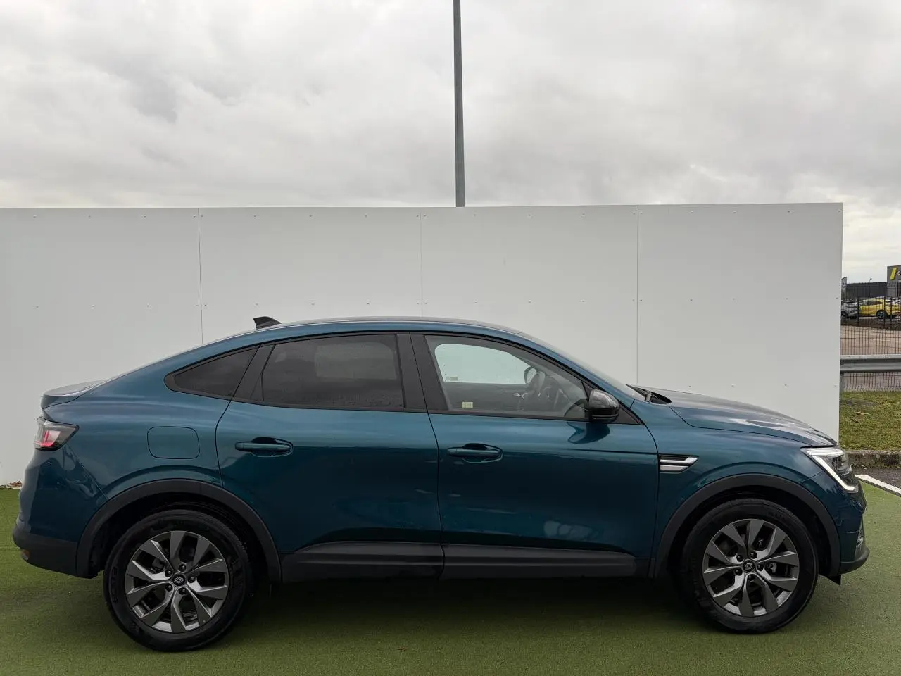 Profil droit du Renault Arkana 2025 bleu Zanzibar métallisé avec vitres surteintées et jantes alliage grises 17 pouces.