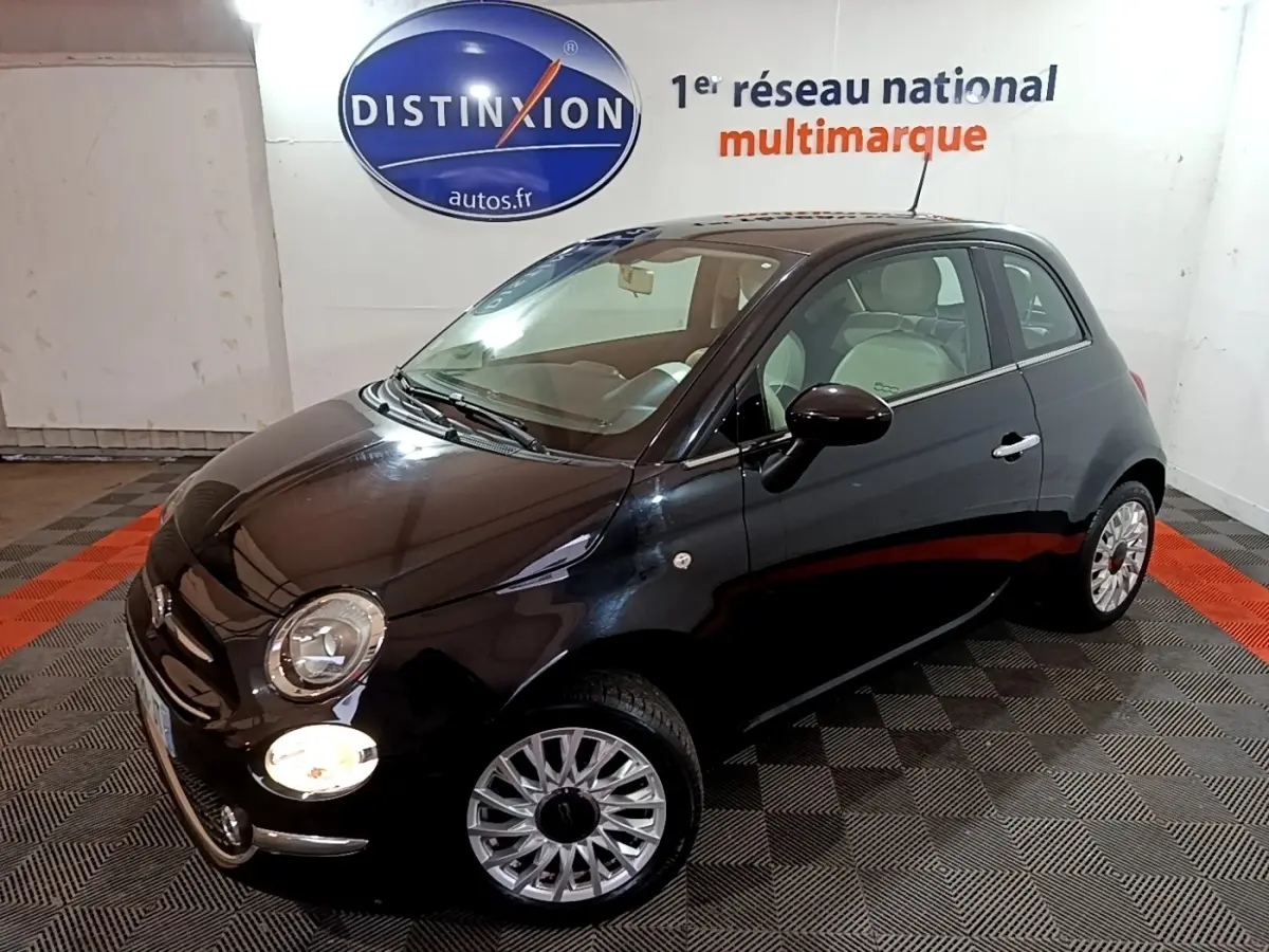 Vue 3/4 avant droit d'une Fiat 500 noire brillante avec jantes argentées dans un showroom intérieur.