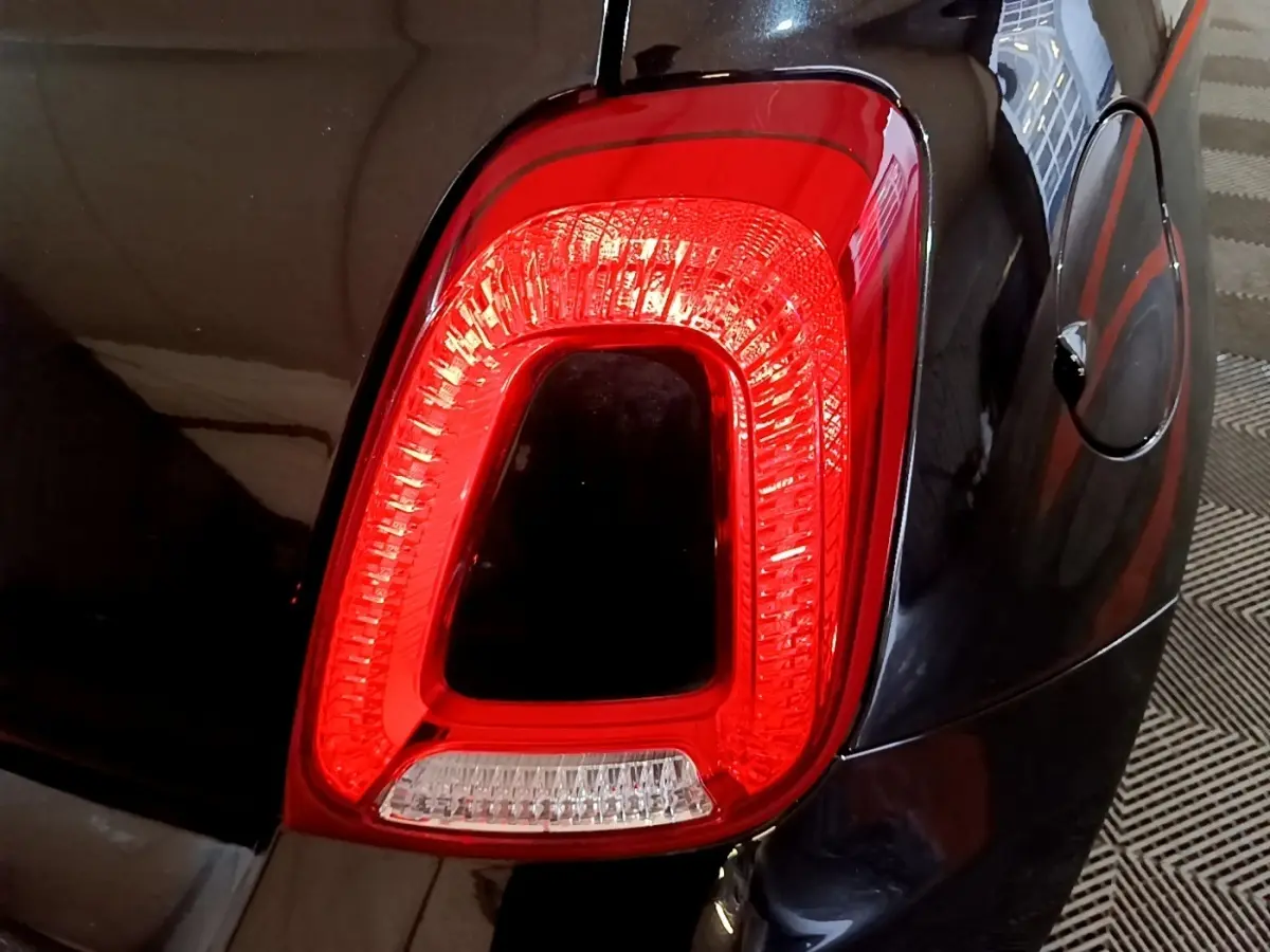Gros plan sur le feu arrière droit rouge de la FIAT 500 noire, avec la trappe à carburant visible à côté.