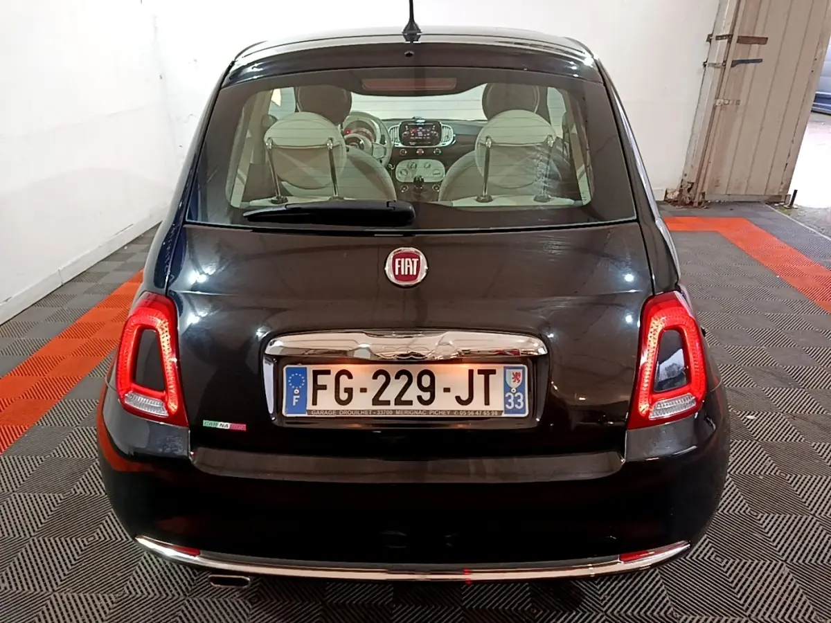 Vue arrière d'une FIAT 500 noire de 2019, avec feux arrière allumés et intérieur visible à travers la lunette arrière.