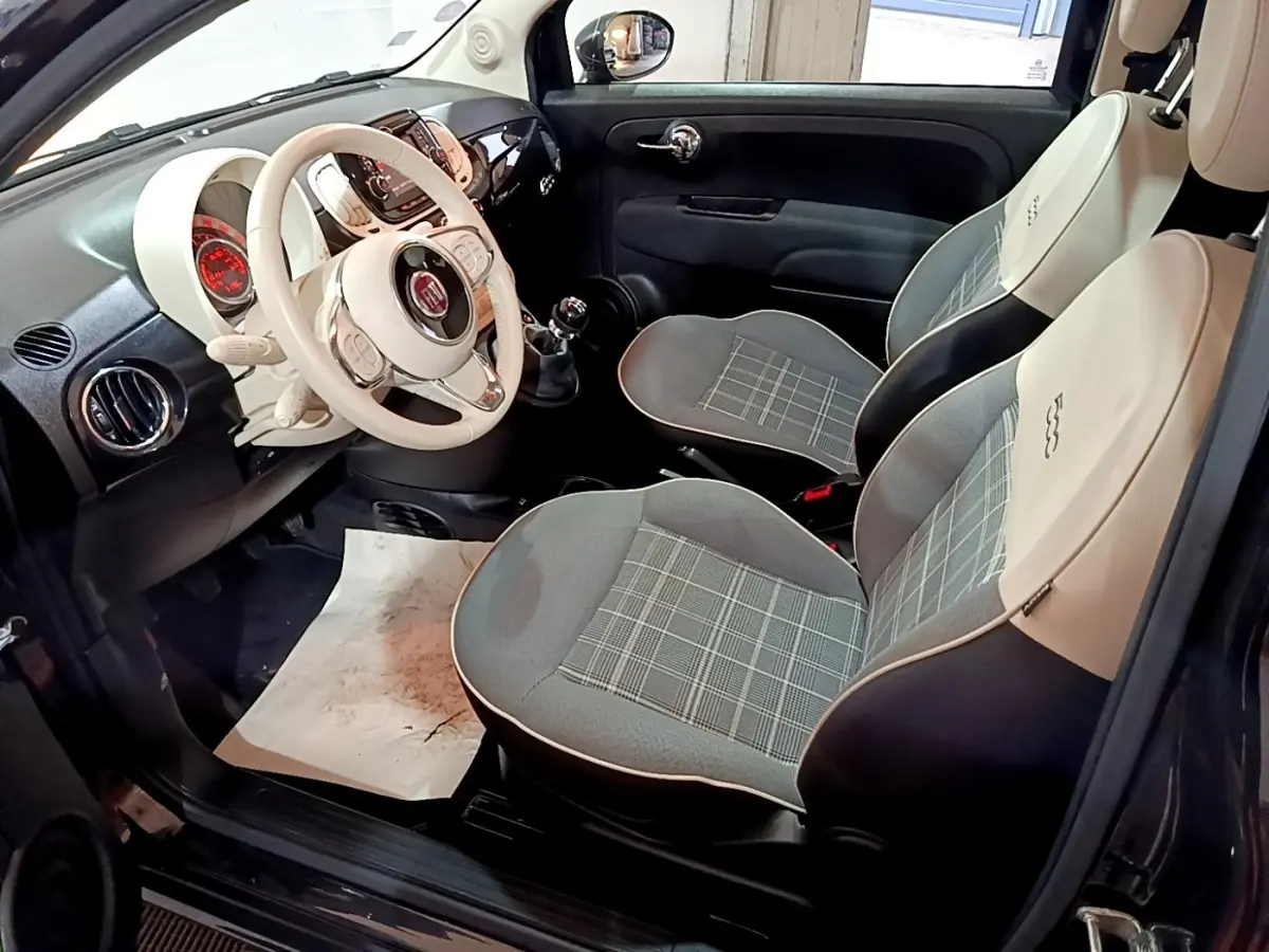 Intérieur de la FIAT 500 Lounge 2019 vu côté conducteur, sièges bicolores gris et beige avec volant cuir blanc.